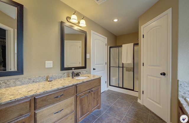 bathroom featuring a closet, vanity, tile patterned flooring, and a shower stall