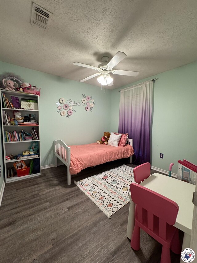 bedroom featuring a textured ceiling, wood finished floors, visible vents, and baseboards