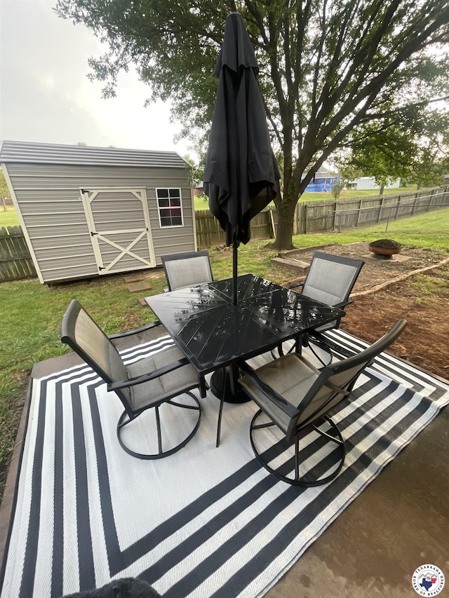 view of patio / terrace with a fenced backyard, an outdoor structure, outdoor dining area, and a shed