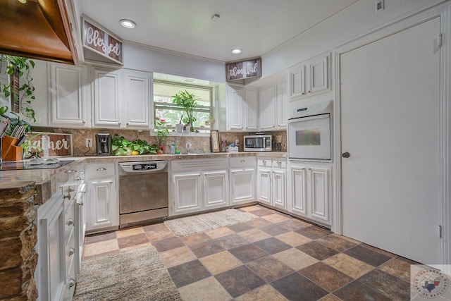 kitchen featuring white oven, dishwashing machine, custom exhaust hood, white cabinets, and backsplash