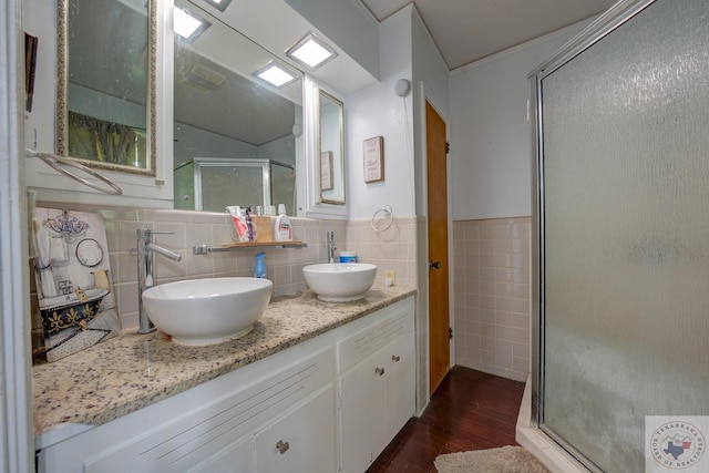 bathroom with a shower with shower door, tile walls, vanity, and hardwood / wood-style floors