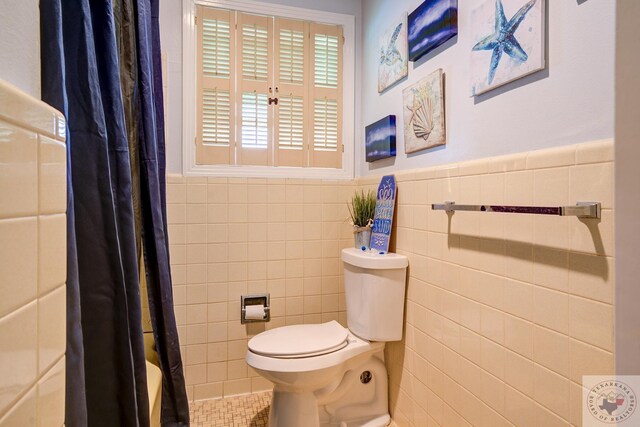 bathroom featuring toilet, walk in shower, and tile walls