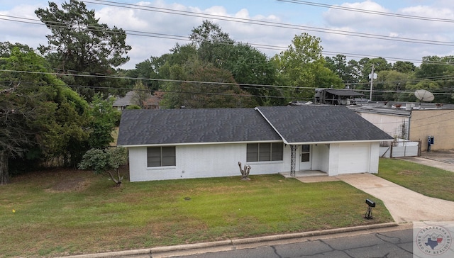 ranch-style home with an attached garage, a front lawn, concrete driveway, and roof with shingles