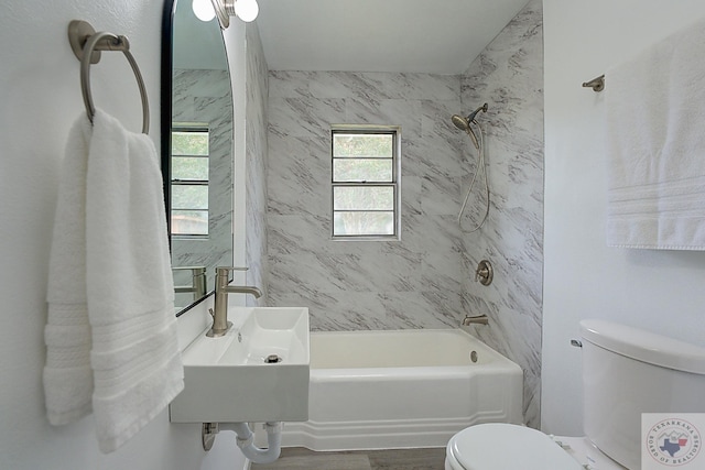 full bathroom with sink, wood-type flooring, toilet, and tiled shower / bath