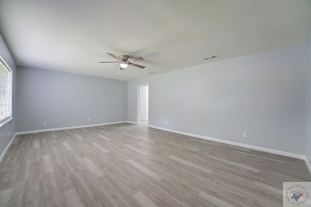 empty room featuring baseboards, visible vents, a ceiling fan, wood finished floors, and a textured ceiling