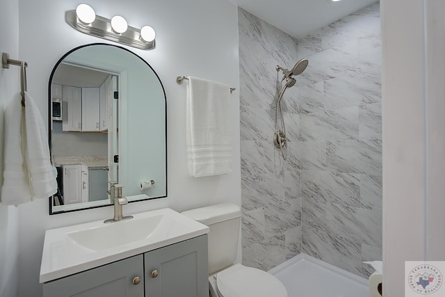 bathroom featuring toilet, vanity, and a tile shower