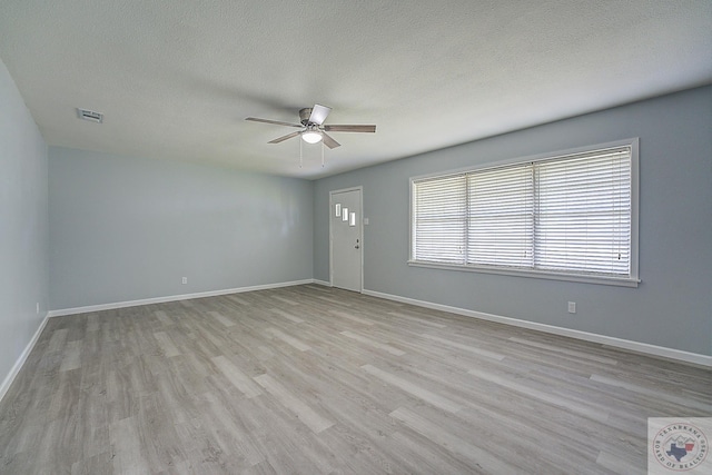 spare room with a textured ceiling, light hardwood / wood-style flooring, and ceiling fan