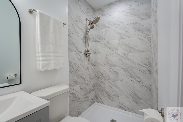 bathroom with toilet, vanity, and tiled shower