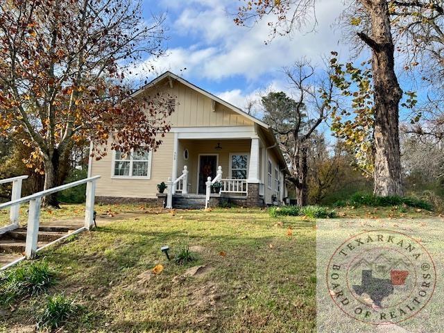 bungalow-style house with covered porch, board and batten siding, and a front yard