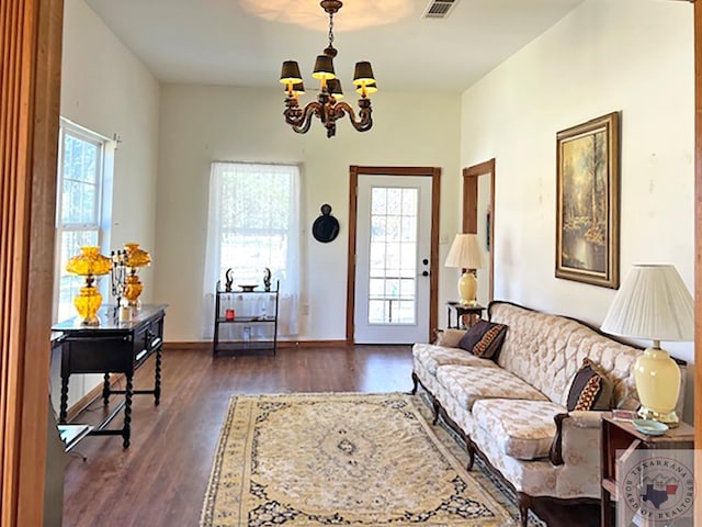 living room with visible vents, a chandelier, and dark wood-style flooring