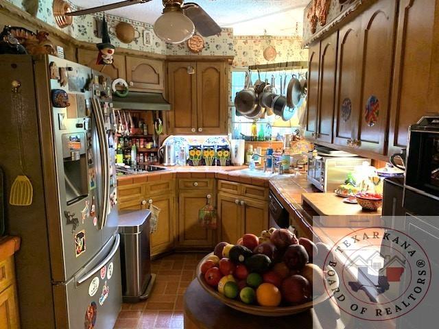 kitchen with sink, black appliances, ceiling fan, and tile counters