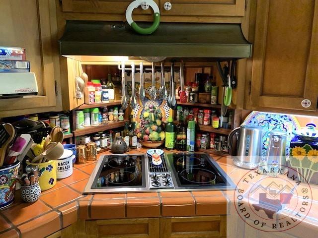 interior space with gas stovetop, ventilation hood, and tile counters