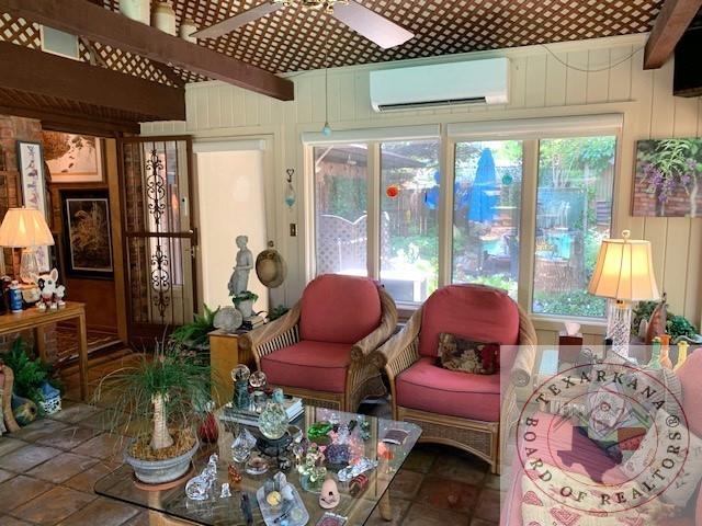 sunroom / solarium featuring ceiling fan, beam ceiling, and a wall mounted air conditioner