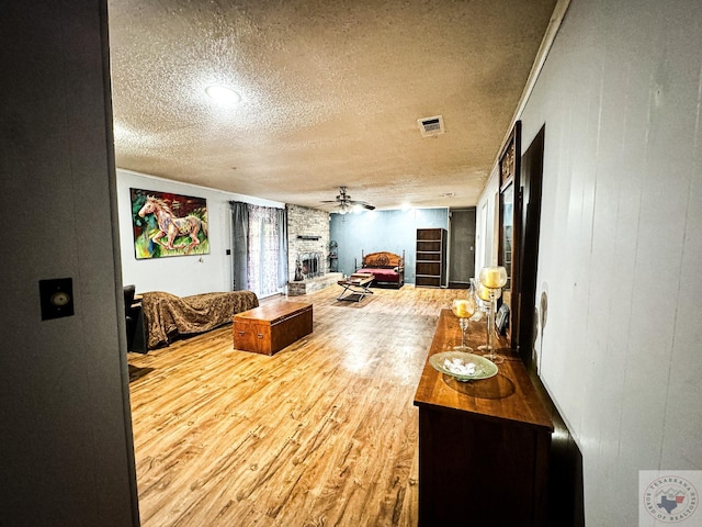 bedroom featuring a stone fireplace, wood walls, hardwood / wood-style floors, and a textured ceiling