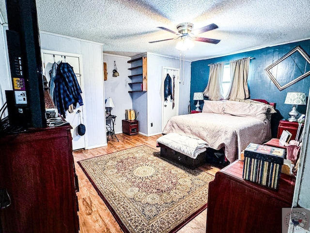 bedroom featuring ceiling fan, light hardwood / wood-style floors, a textured ceiling, and crown molding