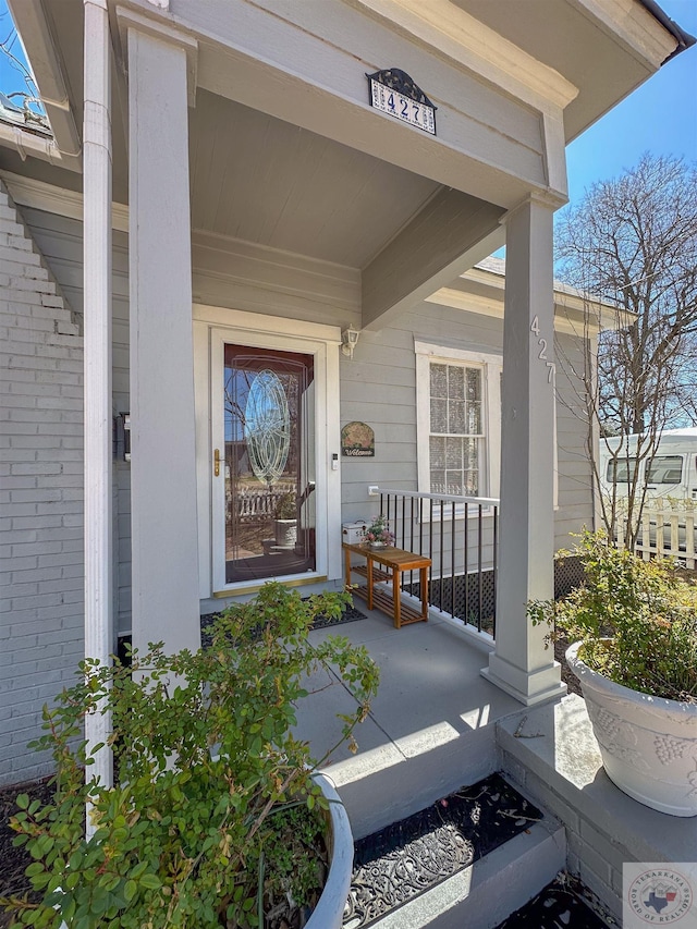 property entrance featuring brick siding and covered porch