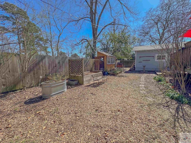 view of yard featuring an outbuilding, a garden, a storage unit, and a fenced backyard