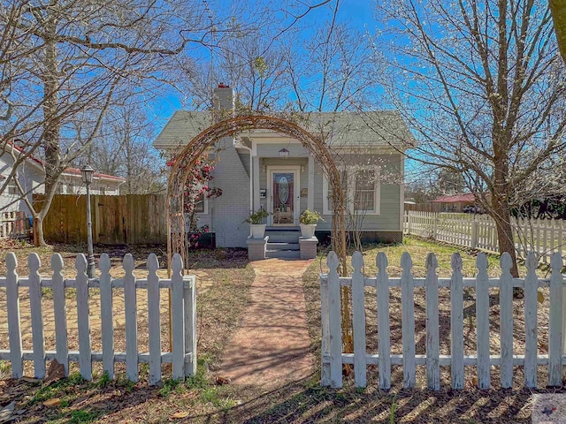 view of front of house featuring brick siding, a fenced front yard, and a chimney