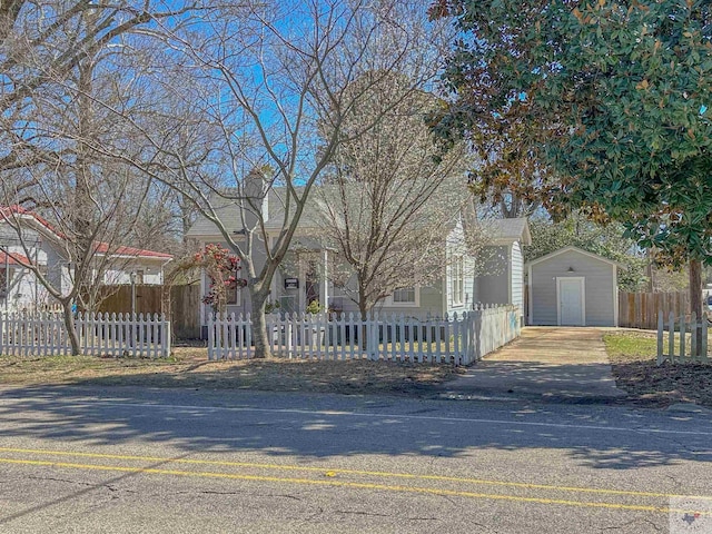 view of front facade with a fenced front yard, a shed, and an outbuilding