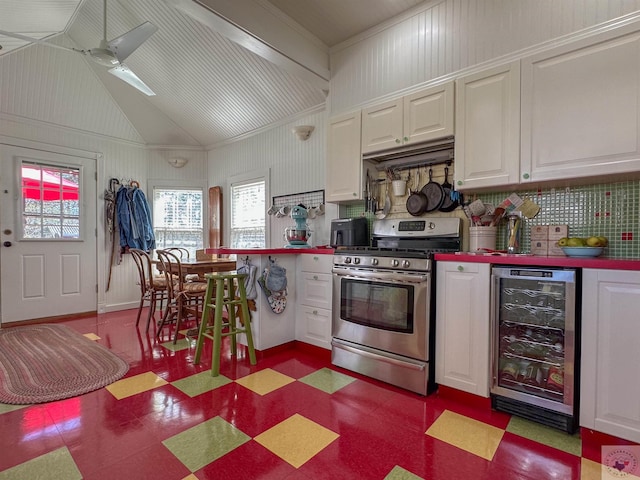 kitchen featuring gas stove, beverage cooler, vaulted ceiling, white cabinets, and dark floors