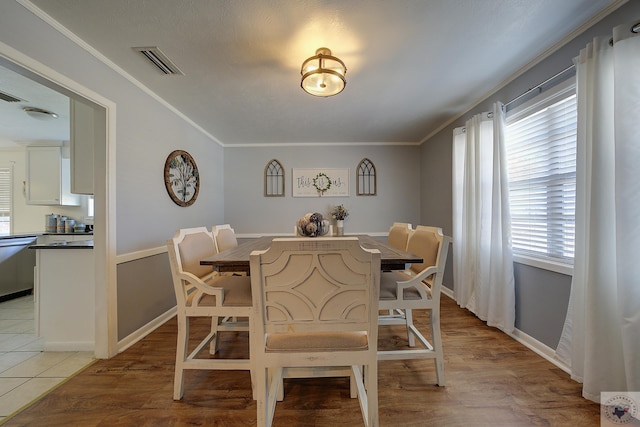 dining area featuring light wood-style flooring, visible vents, and ornamental molding