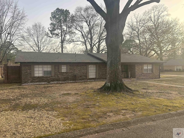 ranch-style house featuring brick siding and fence