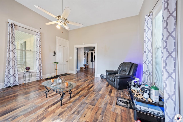 living area featuring wood finished floors, a ceiling fan, and baseboards