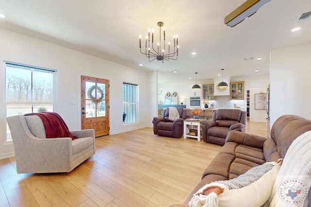 living area featuring a notable chandelier, light wood finished floors, recessed lighting, visible vents, and baseboards