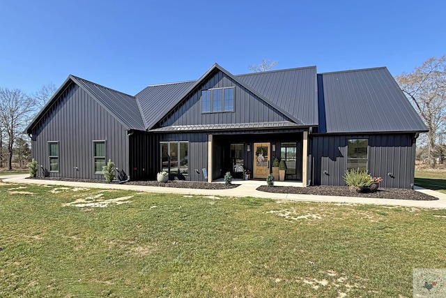 back of house with metal roof, a yard, and board and batten siding