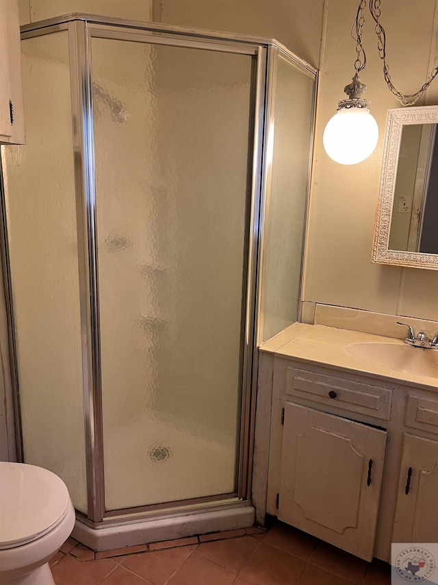 bathroom with tile patterned floors, a shower with door, toilet, and vanity