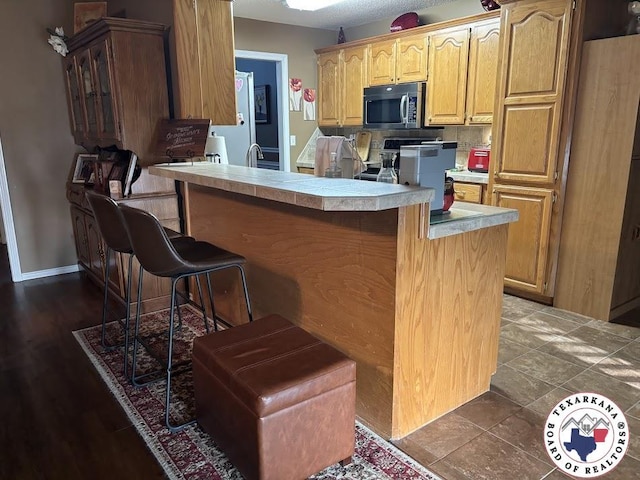 147 Mc 458, Texarkana, AR 71854 - kitchen with stainless steel microwave, a breakfast bar area, stove, light countertops, and a peninsula