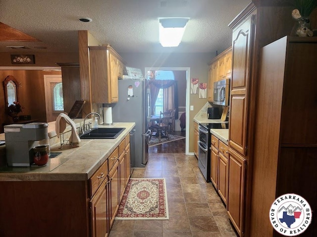 147 Mc 458, Texarkana, AR 71854 - kitchen with appliances with stainless steel finishes, light countertops, a textured ceiling, and brown cabinetry