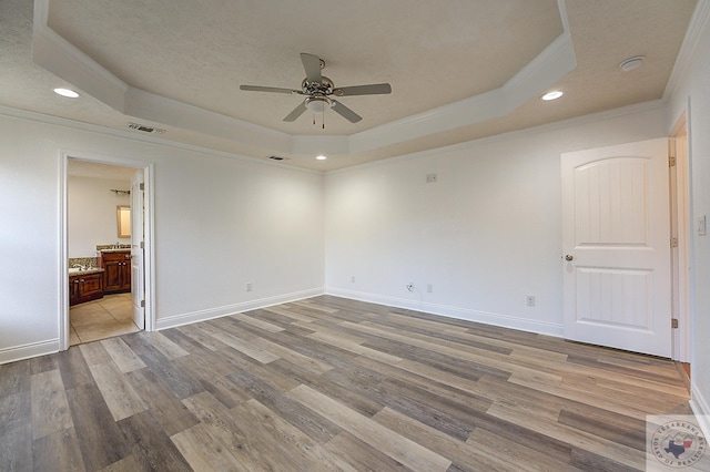 unfurnished room featuring crown molding, light wood-type flooring, ceiling fan, and a tray ceiling