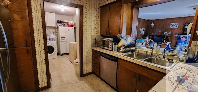 kitchen featuring sink, wood walls, tile counters, dishwasher, and white fridge with ice dispenser