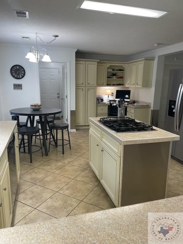 kitchen with black appliances, light tile patterned floors, cream cabinetry, a kitchen island, and pendant lighting