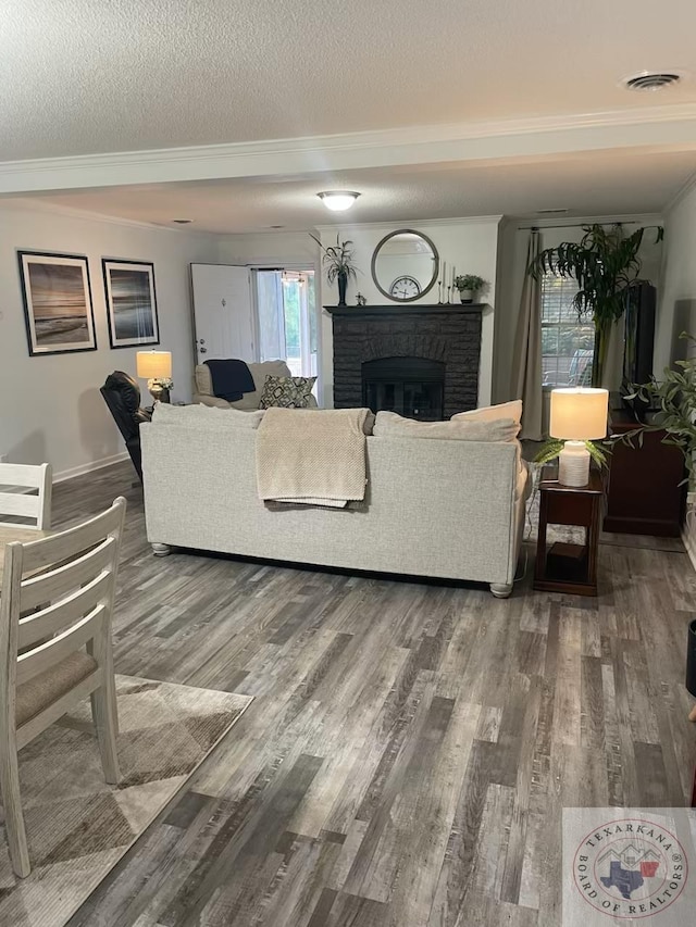 living room featuring a brick fireplace, a textured ceiling, and wood-type flooring