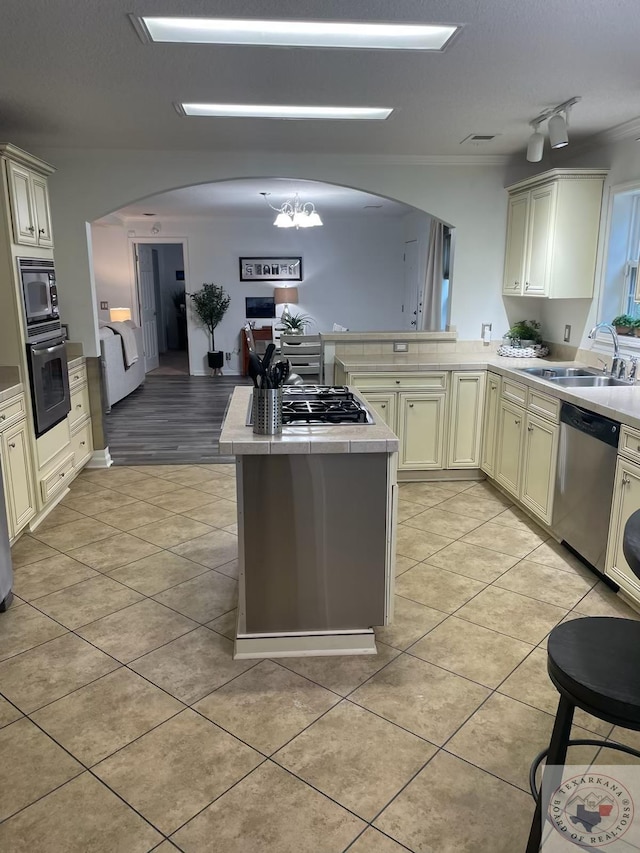 kitchen featuring appliances with stainless steel finishes, a chandelier, light tile patterned floors, sink, and cream cabinetry