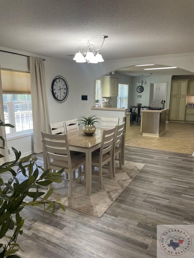 dining room with a textured ceiling, light hardwood / wood-style flooring, and a notable chandelier