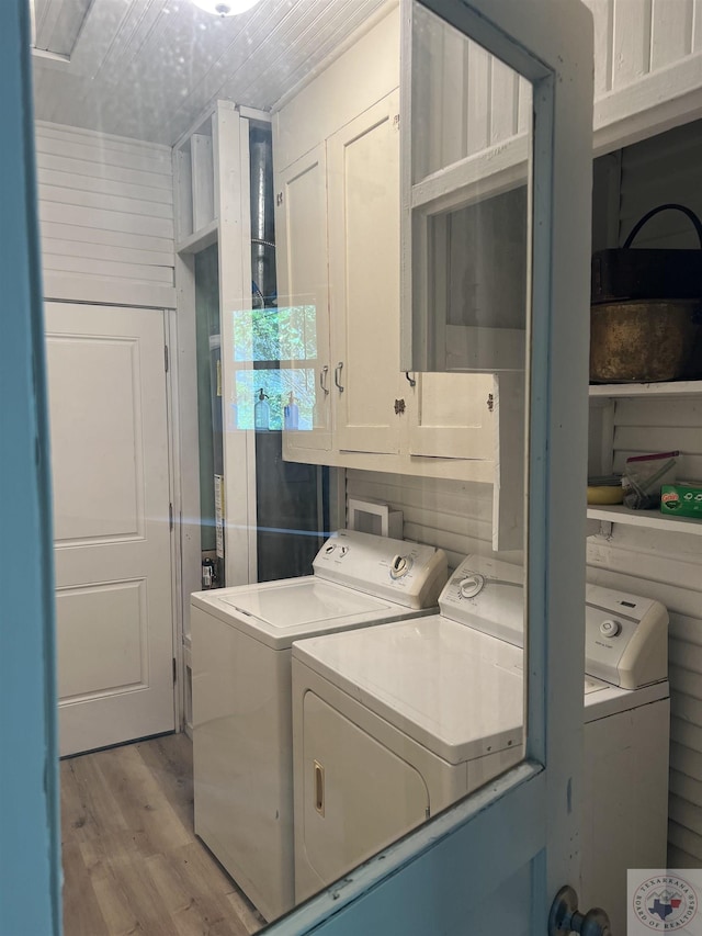 washroom featuring cabinets, light hardwood / wood-style flooring, and washing machine and clothes dryer