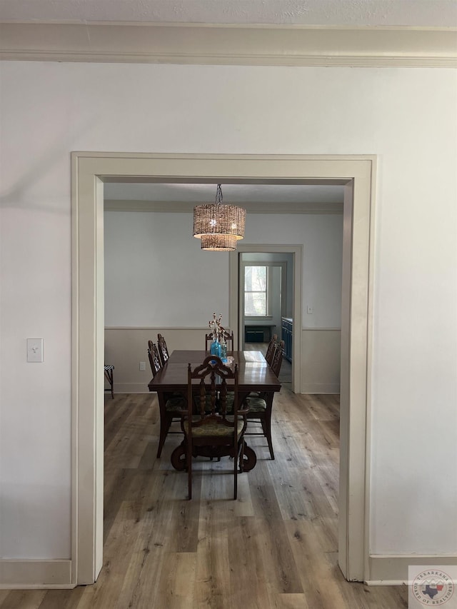 dining area with wood-type flooring, crown molding, and an inviting chandelier