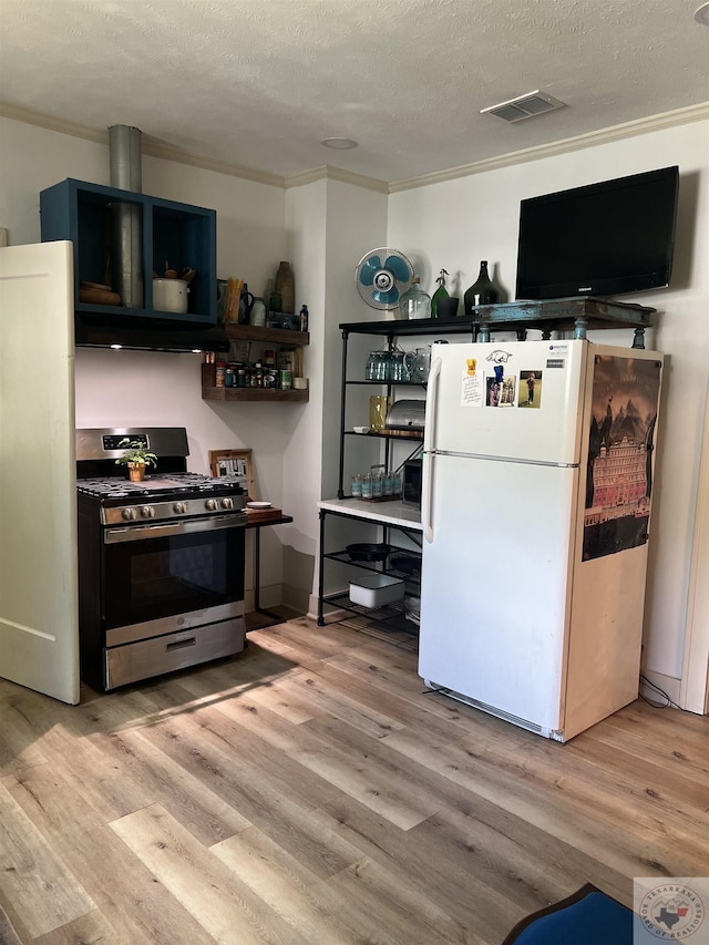 kitchen with light hardwood / wood-style floors, stainless steel gas range, a textured ceiling, and white refrigerator