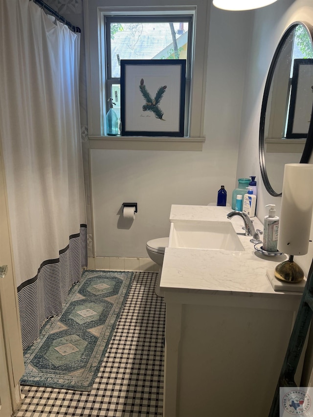 bathroom with toilet, tile patterned floors, a wealth of natural light, and vanity