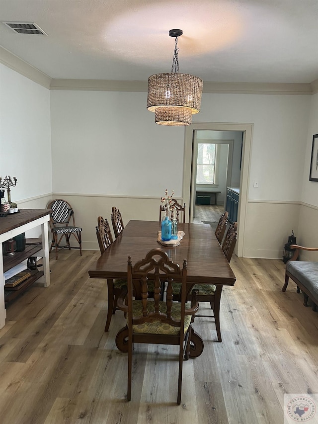 dining area featuring an inviting chandelier, crown molding, and light wood-type flooring