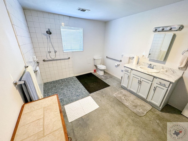 bathroom with tiled shower and vanity