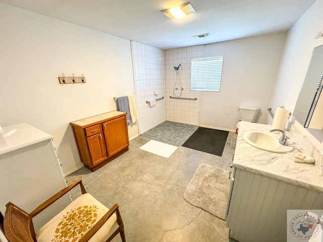 bathroom featuring concrete floors, toilet, vanity, and a tile shower