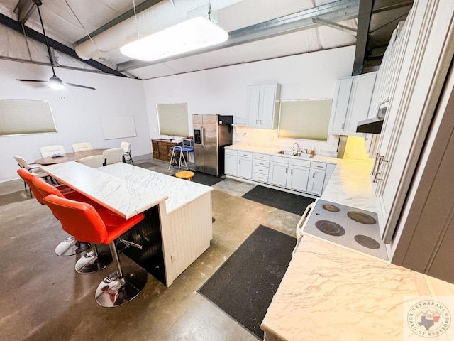 kitchen with stainless steel refrigerator with ice dispenser, sink, white cabinets, electric stove, and a kitchen bar