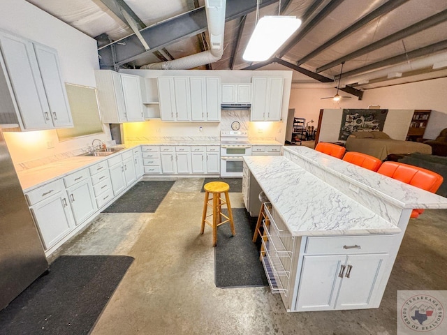 kitchen with a center island, white cabinetry, sink, double oven range, and a breakfast bar