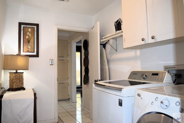 clothes washing area with light tile patterned flooring, cabinets, and washing machine and dryer