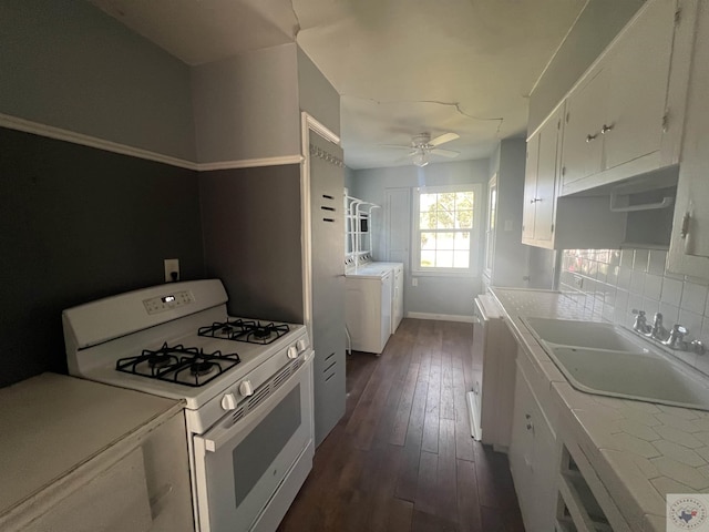 kitchen with washing machine and dryer, white cabinets, sink, dark hardwood / wood-style flooring, and white gas range