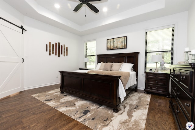 113 Dove Crk, New Boston, TX 75570 - bedroom featuring a tray ceiling, dark wood finished floors, a barn door, a ceiling fan, and recessed lighting